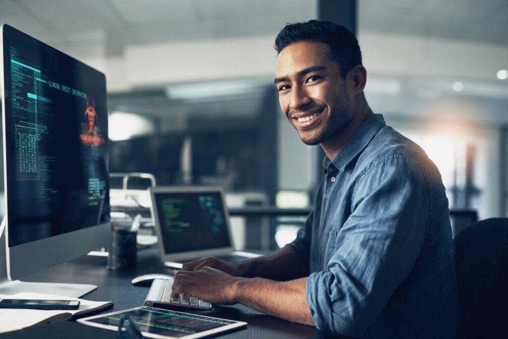 SEO expert smiling at the camera while he is in middle of optimizing a website's code for better performance.