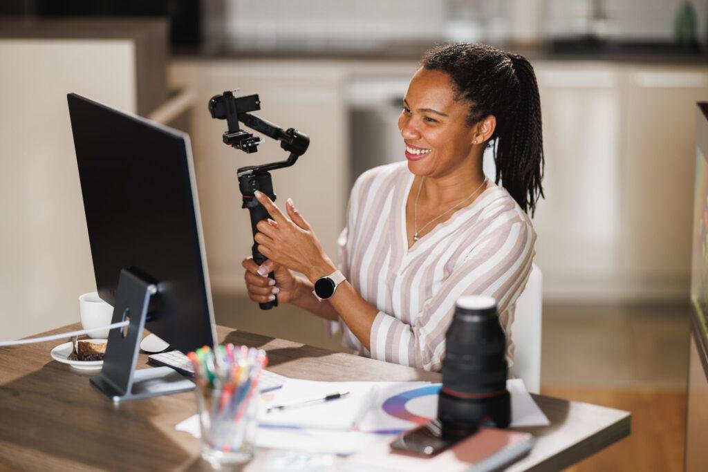 An African creator sharing her passion for photography gear, demonstrating a camera gimbal during a live session on YouTube and Instagram from the comfort of her home